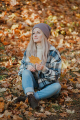 Obraz na płótnie Canvas a blonde girl in a plaid shirt in the autumn forest