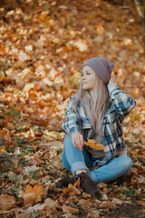 a blonde girl in a plaid shirt in the autumn forest
