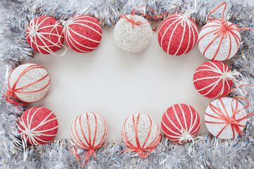 Shiny silver tinsel with white and red Christmas balls borders a blank white background. Top view