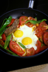 Frying pan with healthy food on a black hob.