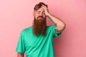 Young caucasian ginger man with long beard isolated on pink background tired and very sleepy keeping hand on head.