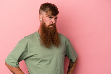 Young caucasian ginger man with long beard isolated on pink background frowning face in...