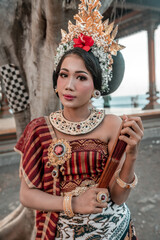 Balinese woman in traditional costume and hand fan, indonesian girl, hindu temple background, Bali.