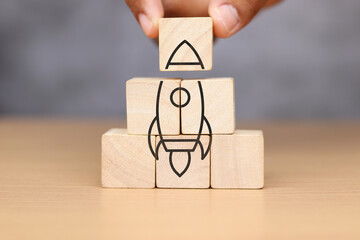 wooden cube with rocket icon on wooden table