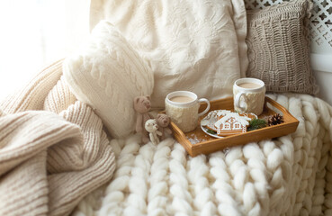 Christmas and New Year composition with a soft plaid, pillows, cookies, gingerbread and coffee. Cozy home and winter concept.