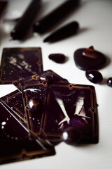 Detail of several black tarot cards with black candles and black stones..