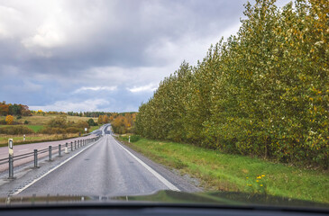 Beautiful view from  front window of a car on highway on an autumn day. Sweden.