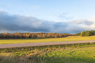 Beautiful autumn nature landscape view. Highway between green fields on blue sky background. Sweden. 