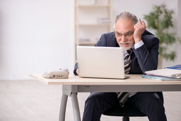 Old male employee working in the office