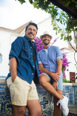 Portrait of gay couple on romantic trip. Two men in casual clothes relaxing in villa, sitting, sightseeing. Love, affection, relationship, travelling concept
