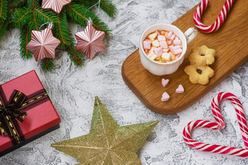 New Year's or Christmas composition of marshmellow cup on wooden stand, spruce green branches, gift, star and lollipops