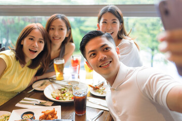 Happy young  people sitting in  restaurant and taking  selfie