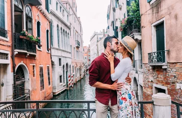 Gartenposter Couple of tourists having a romantic weekend in Venice - Boyfriend and girlfriend in love kissing on city street - Relationship and holidays concept © Davide Angelini