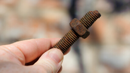 old rusty bolt, iron rod with screw threads, in hand. Rusted mechanical components. holding threaded bolt and nut. dismantling concept, difficult to unscrew, non-removable. isolated, macro photo