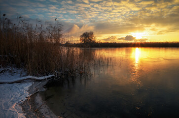 Fototapeta na wymiar Sunrise and frozen sea. Beautiful winter landscape with lake in sunset time.