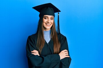 Beautiful brunette young woman wearing graduation cap and ceremony robe happy face smiling with...