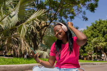 African American teenager listening to music with headphones and mobile