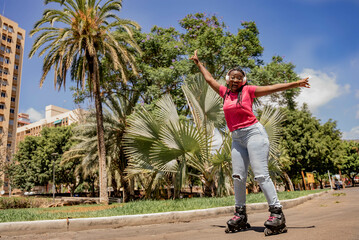 Fototapeta na wymiar African American Teen Having Fun While Rollerblading In The Park