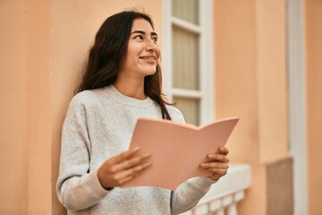 Young middle east student girl smiling happy reading book at the city.