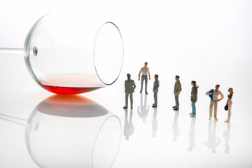 miniature people. men stand near a wine glass with alcohol. alcoholism and addiction problem concept