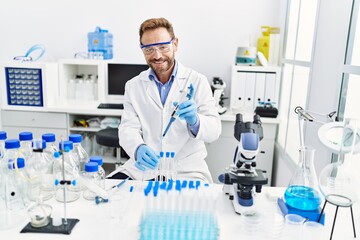 Fototapeta premium Middle age hispanic man wearing scientist uniform working at laboratory