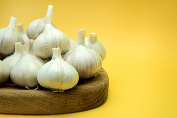 Garlic on a wooden board on a yellow background
