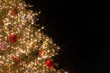 Christmas tree with colourful decorations and sparkling lights against black background