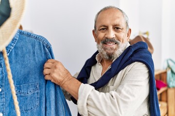 Senior grey-haired man smiling confident shopping at clothing store