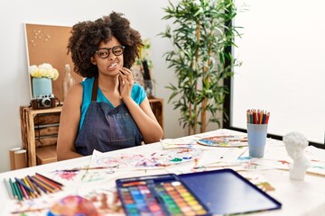 Beautiful african american woman with afro hair painting at art studio touching mouth with hand with painful expression because of toothache or dental illness on teeth. dentist