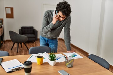 Young hispanic businessman talking on the smartphone working at the office.