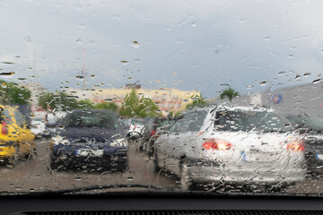 Raindrops on the window glass with outline of a car and a person