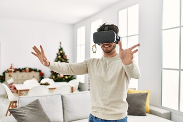 Young hispanic man smiling happy using 3d vr glasses at home.