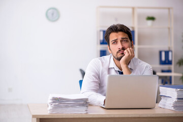 Young male employee unhappy with excessive work in the office