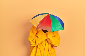Young african american man wearing yellow raincoat with sad expression covering face with hands while crying. depression concept.