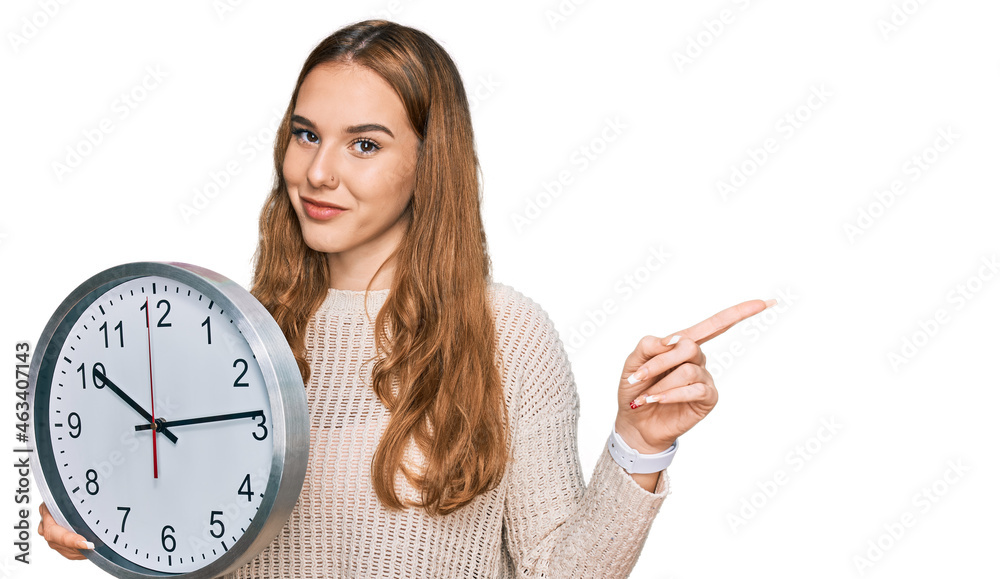 Sticker young blonde woman holding big clock smiling happy pointing with hand and finger to the side