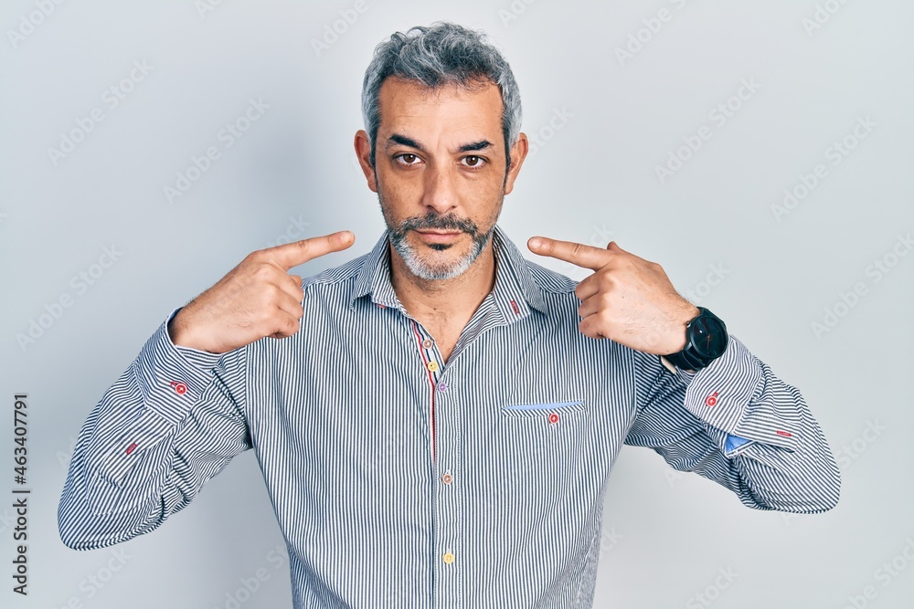 Poster handsome middle age man with grey hair pointing mouth with fingers relaxed with serious expression o