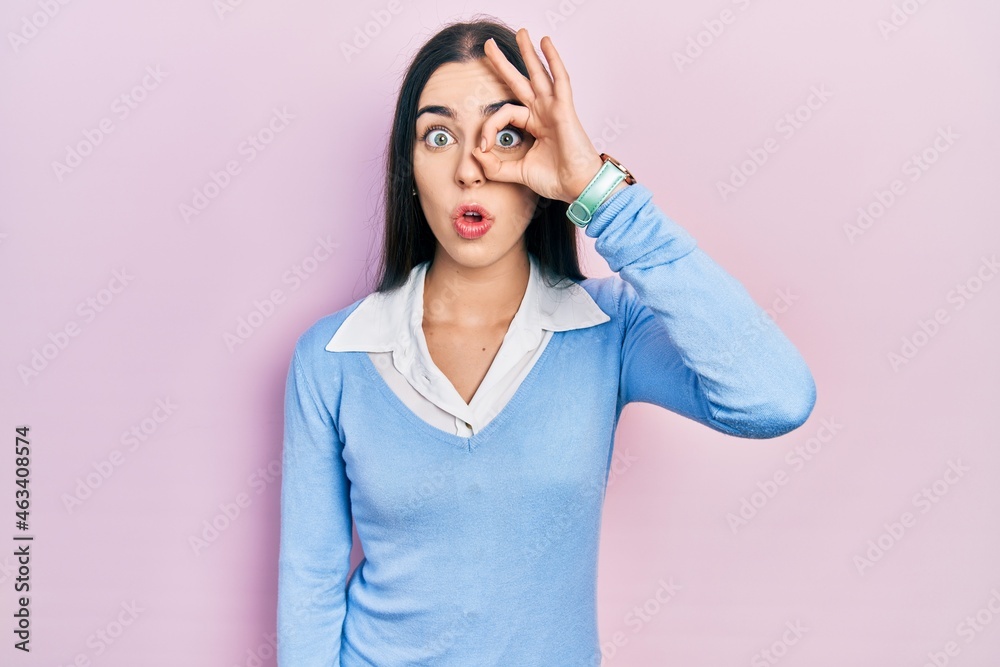 Sticker beautiful woman with blue eyes standing over pink background doing ok gesture shocked with surprised