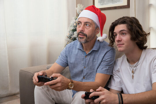 un p&egrave;re de famille joue &agrave; la console de jeux vid&eacute;os avec son fils. Ils ont des manettes entre les mains et ils s'amusent, c'est fun