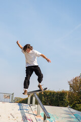 Jeune garçon adolescent aux cheveux longs en train de sauter et de faire des acrobaties avec son...