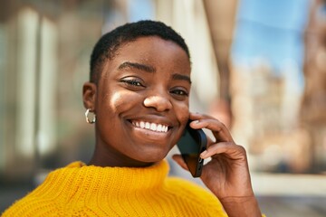 Young african american woman smiling happy talking on the smartphone at the city
