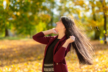 Portrait of a joyful young woman enjoying in the autumn park.