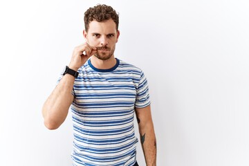 Handsome young man standing over isolated background mouth and lips shut as zip with fingers....