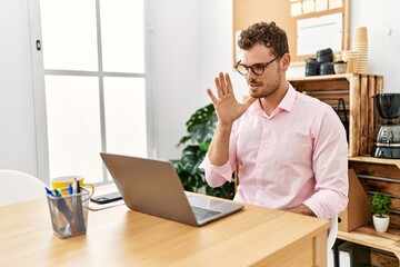 Young hispanic man having video call communicating with deaf sign language at office