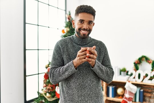 Young african american man drinking coffee celebrating christmas at home.