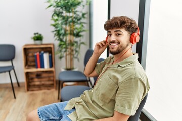 Obraz premium Young arab man listening to music sitting on the chair at waiting room