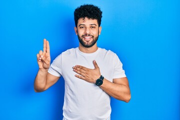 Young arab man with beard wearing casual white t shirt smiling swearing with hand on chest and fingers up, making a loyalty promise oath