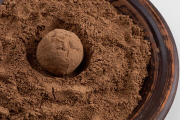 Close-up of date ball in cocoa powder. Healthy chocolate dessert.