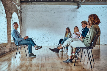 Young man with a flipboard leading a discussion between a group of people sitting in a circle.