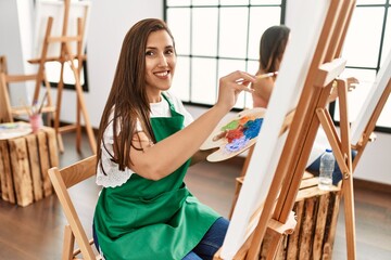 Two latin paint students smiling happy painting at art school.