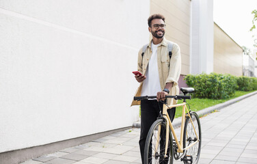 Young handsome man walking with bike and smartphone in a city, Smiling student men with bicycle and...